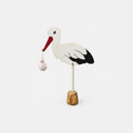 Dekorativer Storch mit kleinem Bündel und Holzsockel – ein besonderer Blickfang bei Tischlein Schmück Dich Fulda.