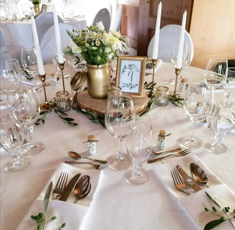 Ein Tisch mit weißen und goldenen Dekorationen, festlich und elegant für eine besondere Gelegenheit gedeckt.