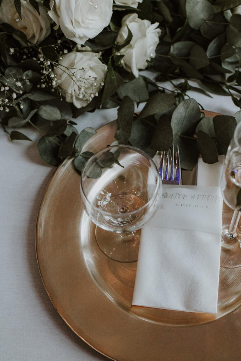 Ein goldener Teller mit Besteck und Blumen darauf.