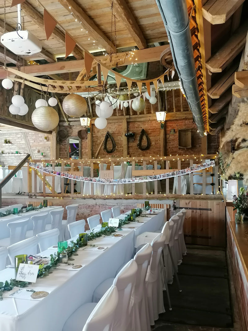 Rustikale Hochzeitsdekoration in Scheune mit Lichterketten, Laternen und Girlanden