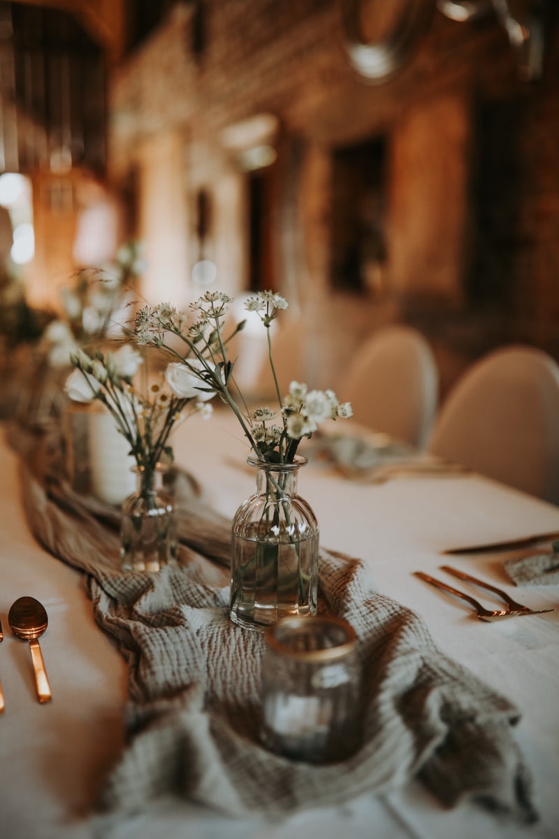 Ein Tisch mit weißen Blumen und silbernem Besteck dekoriert.