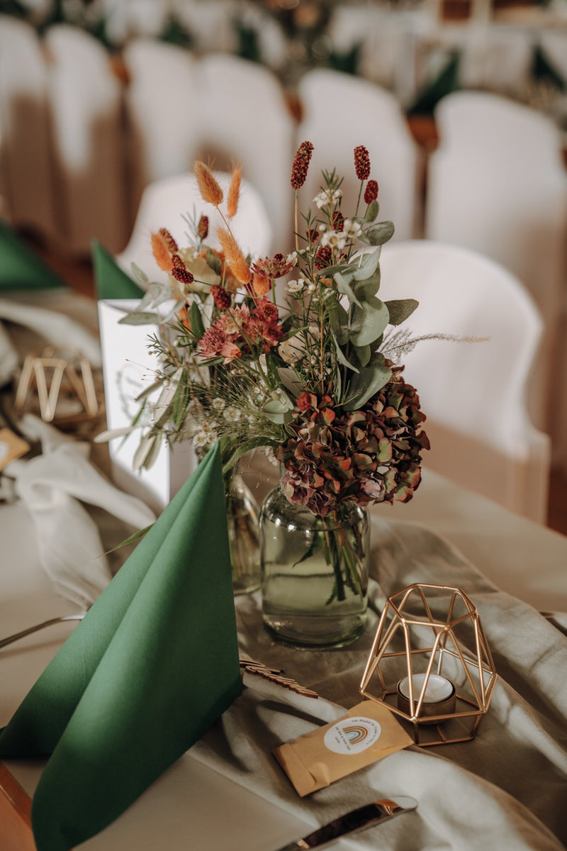Ein Tisch mit grünen Servietten und Blumen dekoriert.