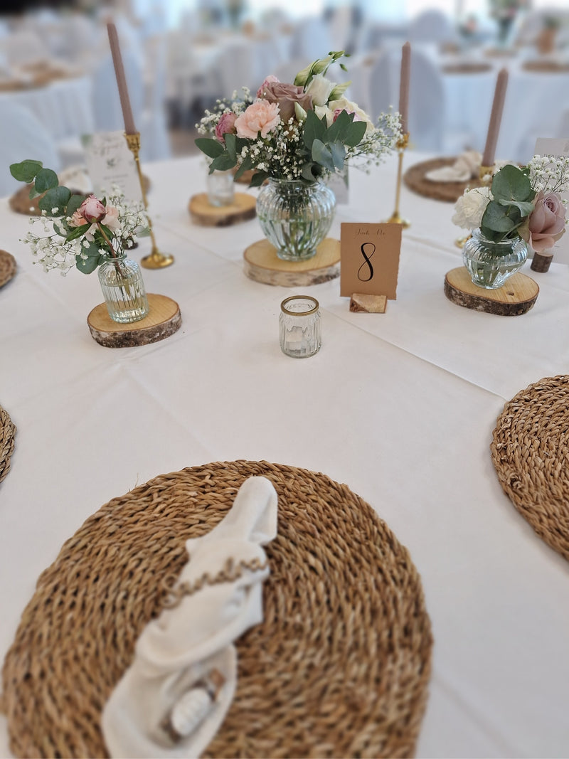 Ein Tisch mit weißen und hölzernen Platzdeckchen, elegant gedeckt für ein festliches Essen.