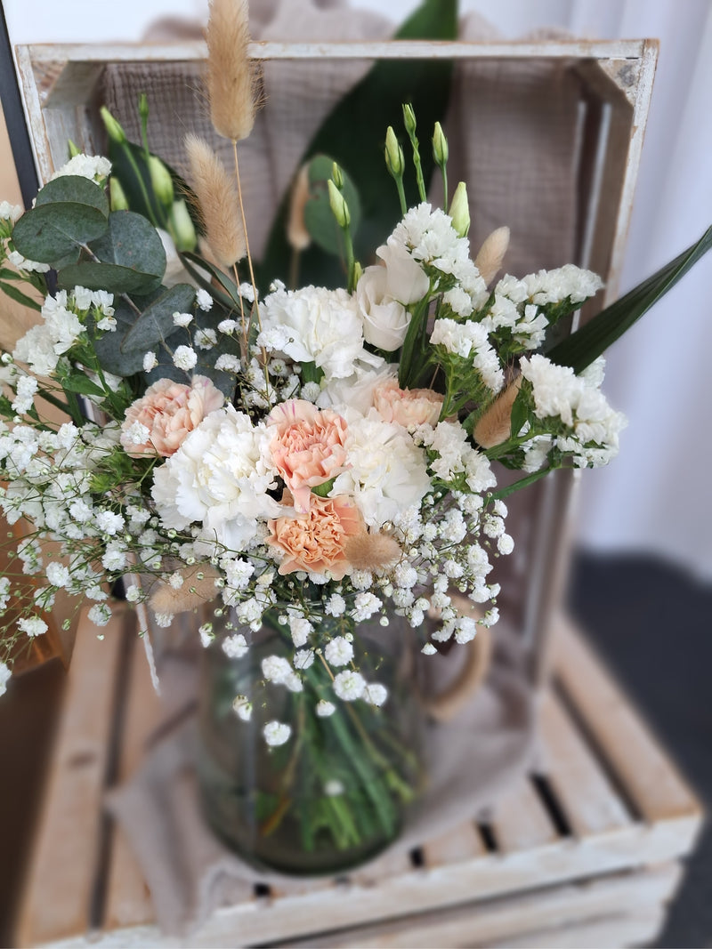 Eine Vase mit weißen und rosa Blumen, die frisch und lebhaft angeordnet sind.